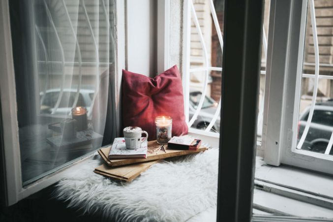 Window seat with pillows, candle, and mug
